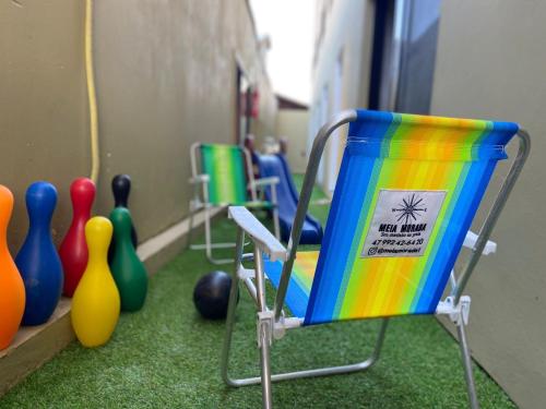 a colorful chair in a room with bowling equipment at Lofts Meia Morada SFS in São Francisco do Sul
