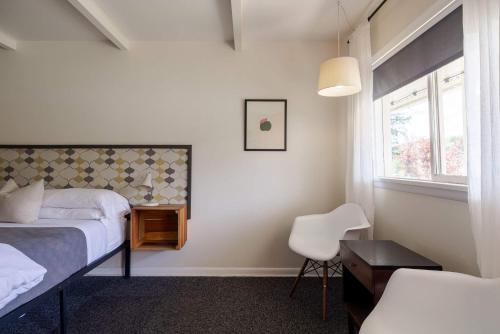 a bedroom with a bed and a chair and a window at The Billy Motel King Room with Retro Charm in Davis