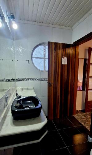 a bathroom with a black toilet and a window at Pousada da Lua in Campos do Jordão