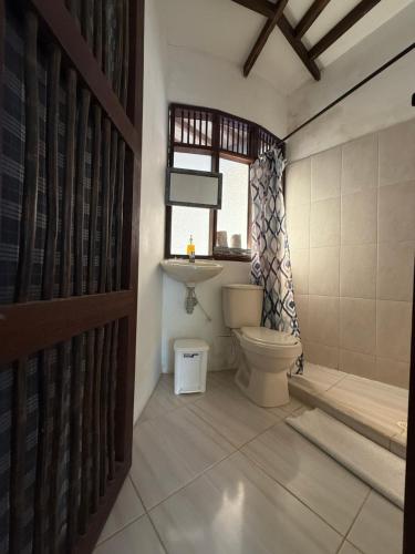 a bathroom with a toilet and a window at Hostal El Bohío in Palomino
