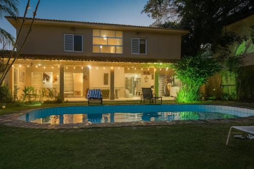 a house with a swimming pool in front of a house at Pousada Mahalo in Guarujá