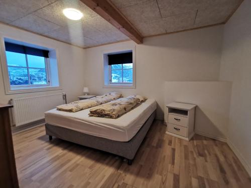 a bedroom with two beds and a table and two windows at Seperat lejlighed i stueetage in Sisimiut