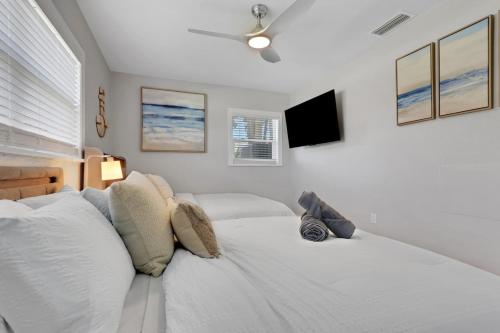 a white bedroom with a bed and a tv at Marco Island Pool, Spa Getaway Fenced Pet Friendly in Marco Island