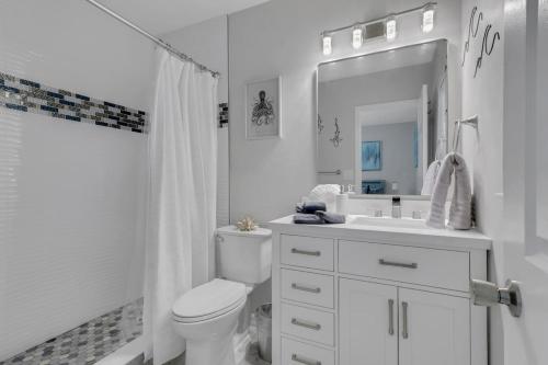 a white bathroom with a toilet and a sink at Marco Island Pool, Spa Getaway Fenced Pet Friendly in Marco Island