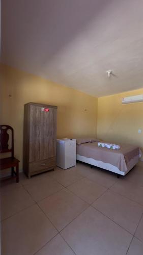 a bedroom with a bed and a refrigerator and a chair at Pousada Rio e Mar in Fortim