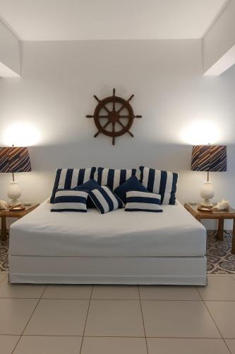 a bed with blue and white pillows and a nautical wheel above it at Pousada Mahalo in Guarujá