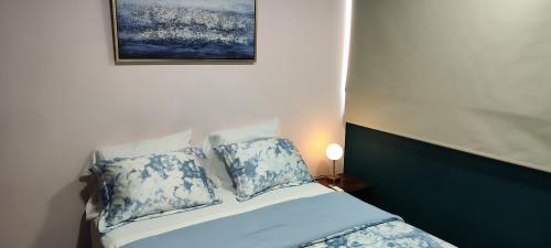 a bed with blue and white pillows and a picture on the wall at La casa de Bába in San Salvador