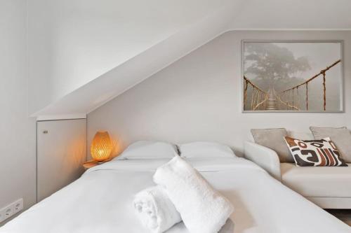a white bedroom with a white couch and a bridge at Modern Limpertsberg Studio Near City Center in Luxembourg