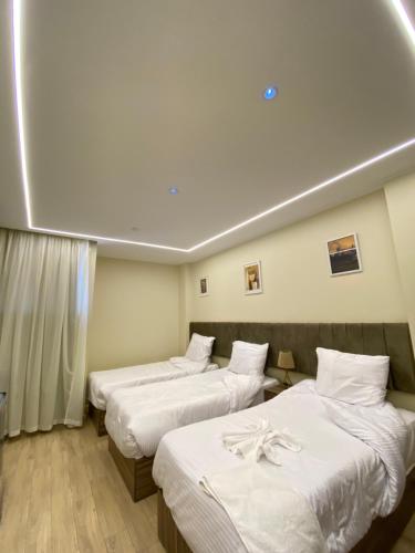 Una habitación de hotel con dos camas con sábanas blancas. en Pyramids Hotel & Free pickup shuttle, en El Cairo