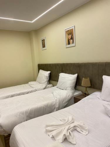 tres camas en una habitación con sábanas blancas en Pyramids Hotel & Free pickup shuttle, en El Cairo