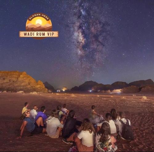 a group of people sitting on the beach at night at WADI RUM NEOM lUXURY CAMP in Wadi Rum