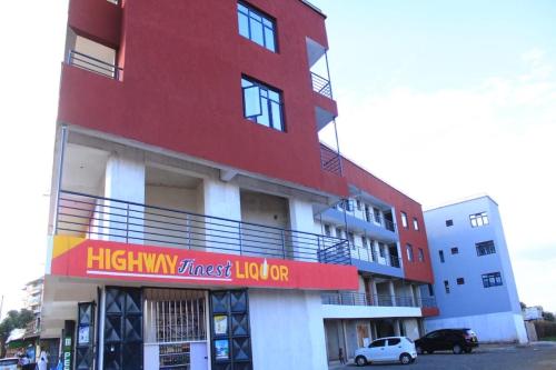een hoog rood gebouw met een bord erop bij Wanjo Cozy Corner in Nyeri
