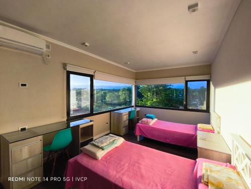 a bedroom with two beds and windows with pink sheets at MIracampo in San Antonio de Arredondo