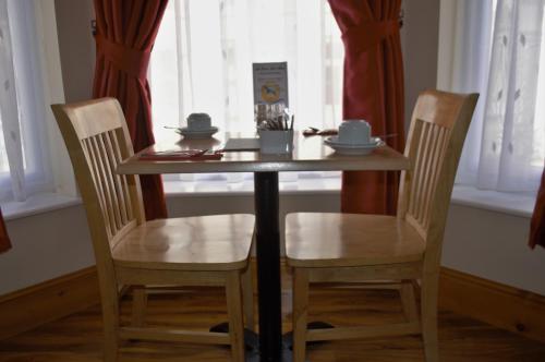 a wooden table with two chairs and a table and two windows at Sea Breeze Guest House in Douglas