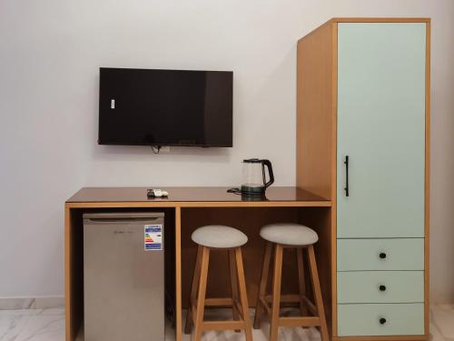 a desk with two stools and a television on a wall at maravilla downtown cairo in Cairo