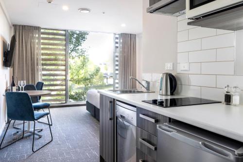 a kitchen with a sink and a table with chairs at Quest on Beaumont in Auckland