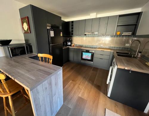 a kitchen with gray cabinets and a wooden counter top at Koala Cottage in Leongatha