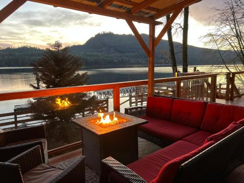 eine Terrasse mit einem Sofa und einem Tisch mit Feuer in der Unterkunft Mile 77 Cottages Lakefront 100yr old Railway Cottage in Youbou