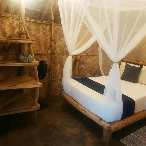 a bedroom with a bed with a mosquito net at Kogui Aldea in Palomino
