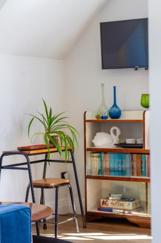 a living room with a book shelf and a tv at Chic Colourful Loft in the Heart of Merivale in Christchurch