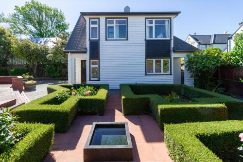 a garden with trimmed hedges in front of a house at Chic Colourful Loft in the Heart of Merivale in Christchurch