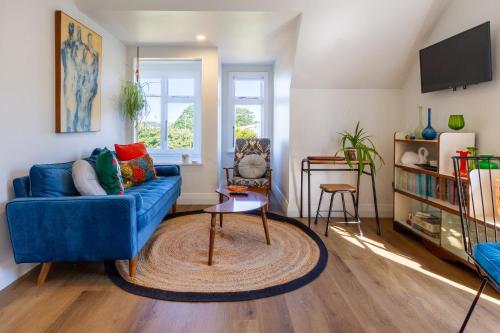 a living room with a blue couch and a table at Chic Colourful Loft in the Heart of Merivale in Christchurch