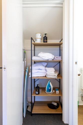 a closet with wooden shelves and towels on it at Chic Colourful Loft in the Heart of Merivale in Christchurch
