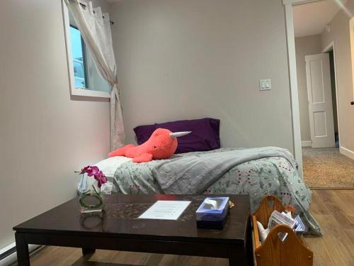 a bedroom with a bed with a table and a red stuffed animal at A Cozy 2 beds Suite in Whistle Bend in Whitehorse