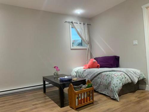 a bedroom with a bed with a table and a window at A Cozy 2 beds Suite in Whistle Bend in Whitehorse