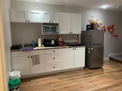 a kitchen with white cabinets and a stainless steel refrigerator at A Cozy 2 beds Suite in Whistle Bend in Whitehorse