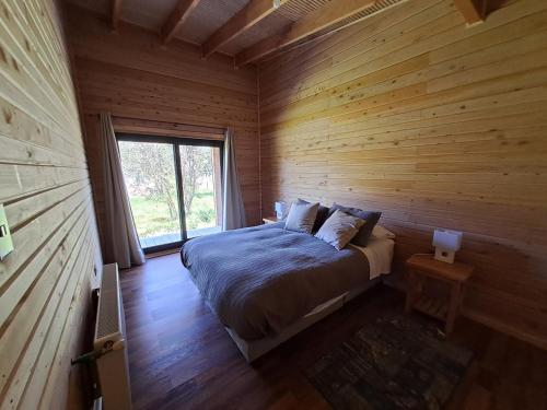 a bed in a wooden room with a window at Wehuilli Puelo in Cochamó