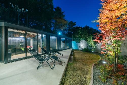 a house with two chairs on a porch at night at private your resort ITTEKURAi 松山 in Kawakami