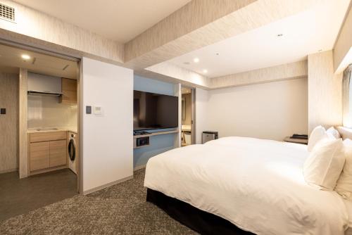 宇都宮市にあるリッチモンドホテル宇都宮駅前アネックスの大きな白いベッドとキッチンのある寝室