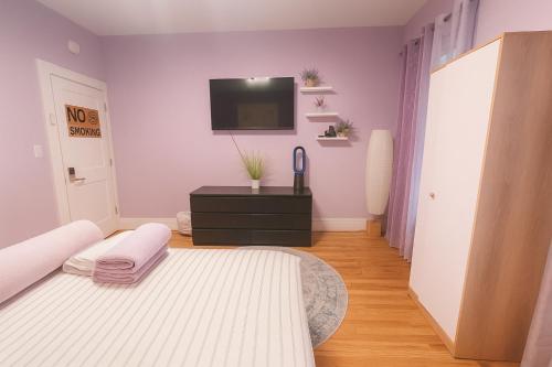 a bedroom with a bed and a tv on the wall at Lavender style Room in New York