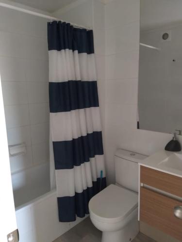 a bathroom with a toilet and a shower curtain at Departamento en Papudo laguna con acceso a la playa in Quinquimo