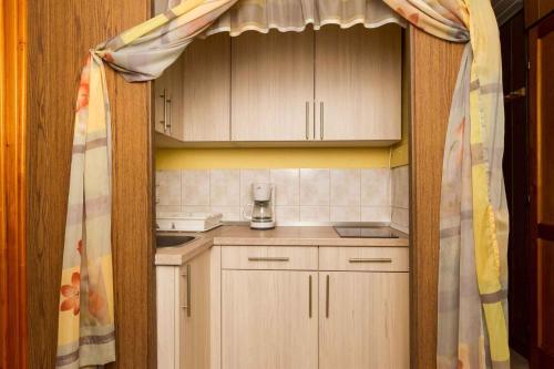 - une petite cuisine avec des placards en bois et un rideau dans l'établissement Holiday home in Balatonmariafürdo 19260, à Balatonmáriafürdő