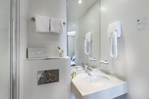 a white bathroom with a sink and a mirror at Logis Hôtel - La Résidence du Berry in Versailles