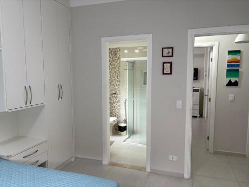 a white bedroom with a shower and a bathroom at Apartamento completo, 200mts da praia de Pitangueiras in Guarujá