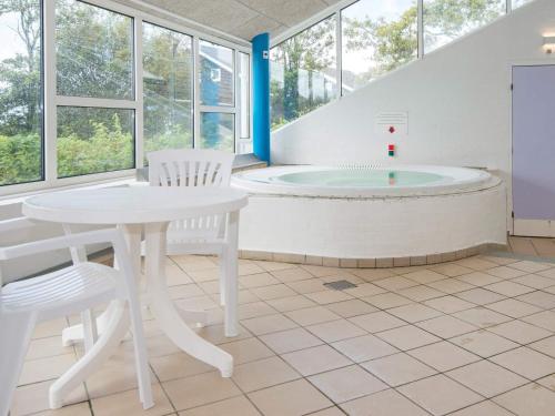 La salle de bains est pourvue d'une baignoire, d'une table et de chaises. dans l'établissement 4 person holiday home on a holiday park in Hemmet, à Hemmet