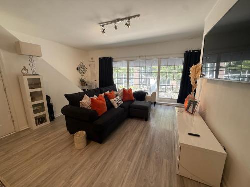 a living room with a black couch and orange pillows at Luxury Midtown Atlanta Condo Walk to Shops & Restaurants in Atlanta