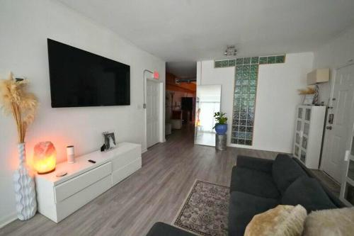 a living room with a couch and a tv on a wall at Luxury Midtown Atlanta Condo Walk to Shops & Restaurants in Atlanta