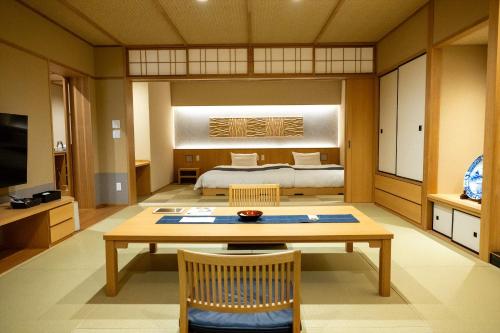 a room with a bed and a table and chairs at Dantokan Kikunoya in Otsu