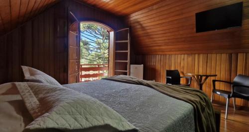 een slaapkamer met een bed en een tv aan de muur bij Pousada da Lua in Campos do Jordão