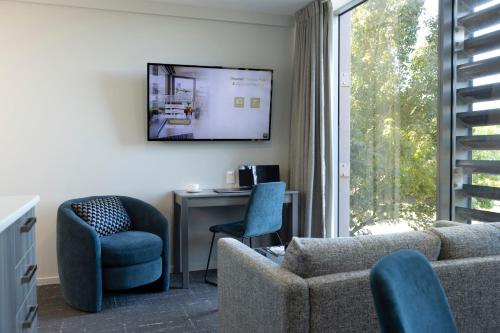 a living room with a couch and a desk and a tv at Quest on Beaumont in Auckland