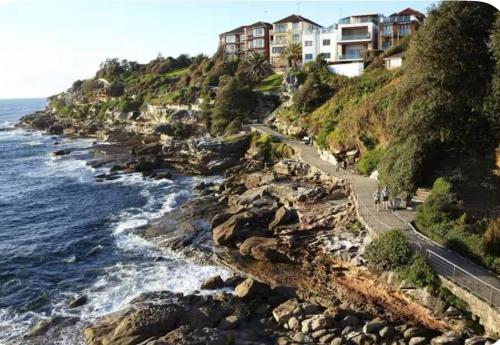 einen Blick auf eine felsige Küste mit Häusern und das Meer in der Unterkunft Bondi Palms in Sydney
