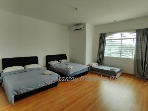 a bedroom with two beds and a window at Homezstay Merdeka Miri in Miri