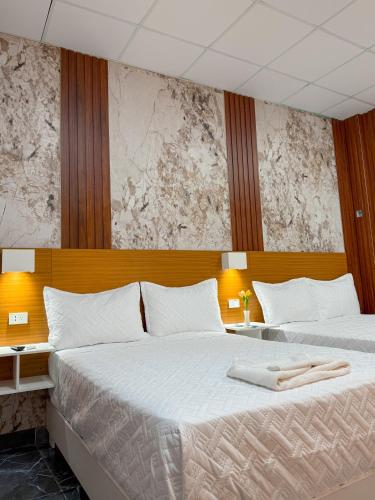 two beds in a hotel room with white sheets at Hotel baramar moca in Moca