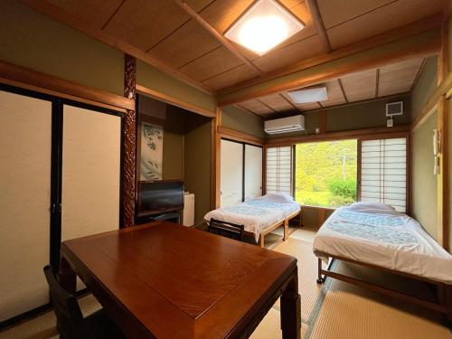 a room with two beds and a table and a desk at Minshuku Ryokan Kawai in Shinshiro