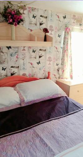 a bedroom with a bed and a window with flowers at Ref G The Chase Caravan Park 3 bed 8 berth in Ingoldmells
