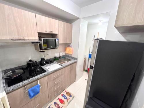 a kitchen with a black refrigerator and a sink at Team Renacer Broker Brisas del Mar and Pool in Cartagena de Indias